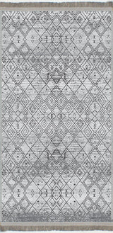 Alfombra 'Anissa' sobre fondo blanco, con un diseño geométrico en tonos grises y negros. Destacan los patrones de rombos y detalles intrincados, con un acabado sutilmente desgastado que le da un toque vintage. La alfombra es lavable en lavadora y tiene una base antideslizante.