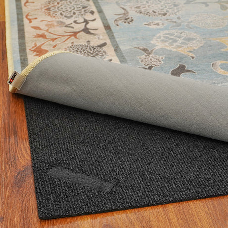 Vista de la alfombra 'Ariel' mostrando la capa superior con su diseño floral y ornamental en colores suaves, junto con la capa inferior antideslizante diseñada para ofrecer estabilidad. La alfombra es lavable en lavadora y no suelta pelusa.